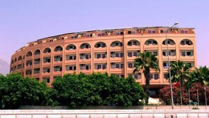 A multi-story building with a curved facade, numerous balconies, and a flat roof. - Doris Aytur (Alanya)