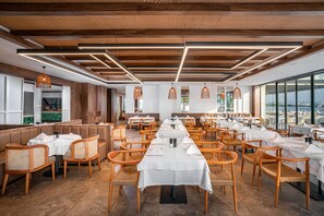 A spacious restaurant with long tables, wooden chairs, and a view of the water. - Yalihan Aspendos Hotel (Alanya)