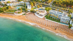 An aerial view of a coastal hotel with a beach, multiple swimming pools, and a variety of building structures. - Yalihan Aspendos Hotel (Alanya)