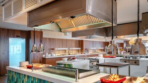 A modern kitchen with stainless steel appliances, a central island with a built-in grill, and a view of the cityscape through the window. - Yalihan Aspendos Hotel (Alanya)