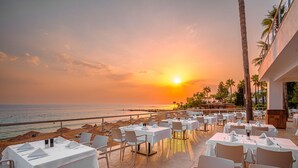 A seaside restaurant with tables set for dining, overlooking the beach and ocean. - Yalihan Aspendos Hotel (Alanya)