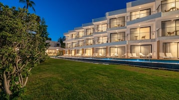 A modern hotel with a pool, multiple balconies, and a well-maintained lawn.