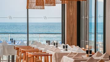 Un espace repas avec des tables dressées, offrant une vue sur la mer.