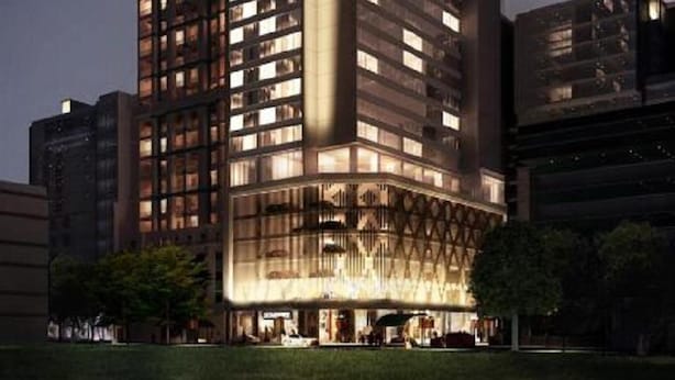 Un hotel moderno con un llamativo letrero 'Somerset', que presenta una estructura de varios pisos con ventanas iluminadas y una entrada bien iluminada.