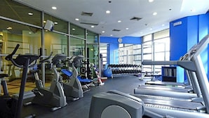 Un gimnasio con cintas de correr, elípticas y equipo de levantamiento de pesas.