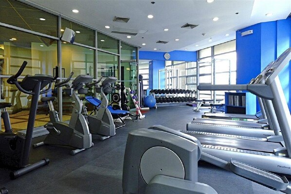 Ein Fitnessstudio mit Laufbändern, Crosstrainern und Gewichten.