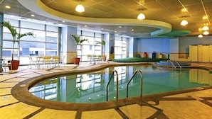 Una piscina interior de diseño curvo, rodeada de zonas de estar y plantas en macetas.