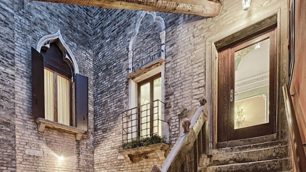 A stone building with a wooden staircase and a balcony. - Pausania Hotel (Venice)