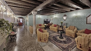 A spacious living room with a high ceiling and exposed beams, furnished with beige sofas and a central coffee table. - Pausania Hotel (Venice)