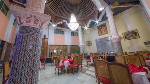 Un comedor con columnas decorativas, candelabros y paredes con diseño.