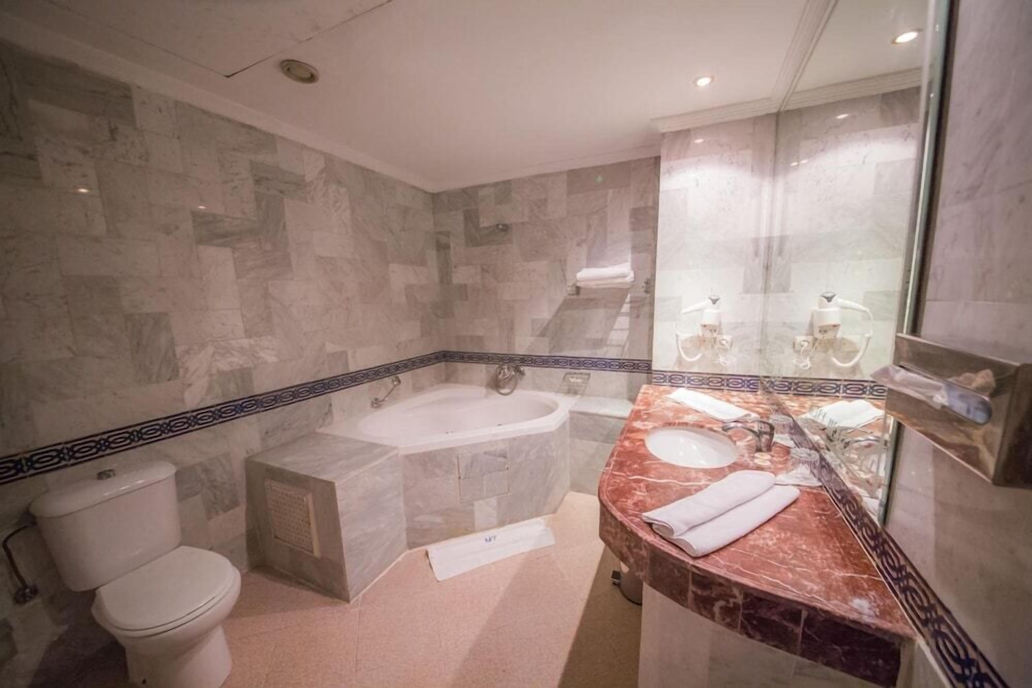 A bathroom with a marble sink, a bathtub, and a toilet.