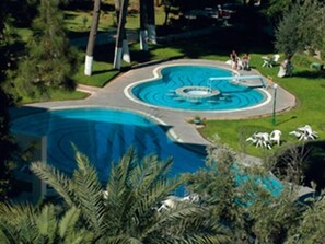 A swimming pool with a circular design, surrounded by a grassy area and trees. - Menzeh Fes (Fes)
