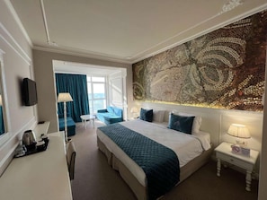 A hotel room with a bed, a desk, a chair, a sofa, a TV, and a large decorative wall. - Adriatik Hotel, BW Premier Collection (Durrës)