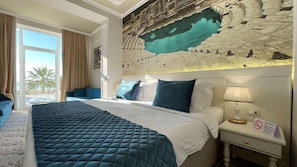 A hotel room with a large bed, a sofa, a nightstand with a lamp, and a view of a pool and outdoor area. - Adriatik Hotel, BW Premier Collection (Durrës)