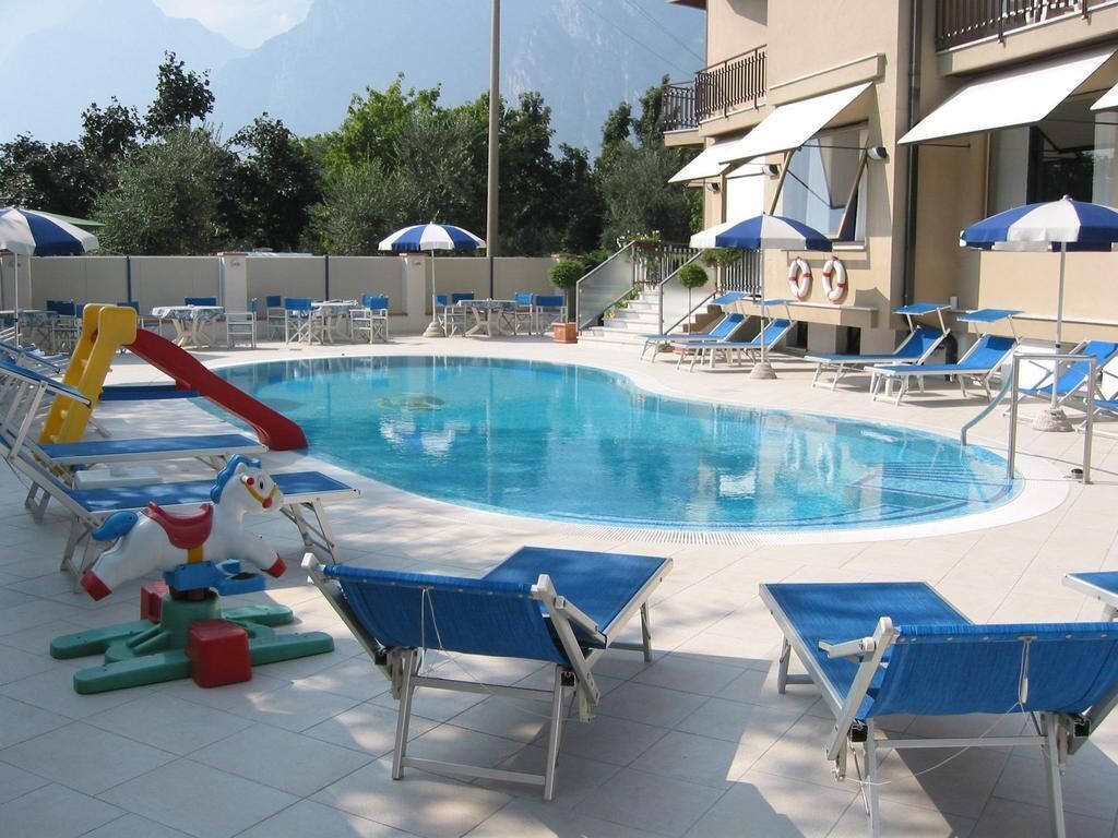 A pool area with blue lounge chairs, a children's play structure, and umbrellas.