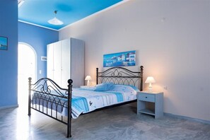 A bedroom with a bed, nightstands, a wardrobe, and a painting on the wall. - Ammes Hotel & Apartments (Kefalonia)