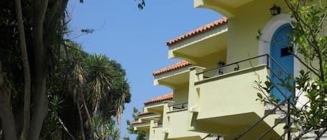 Un edificio de varios pisos con balcones y una escalera, bajo un cielo despejado.