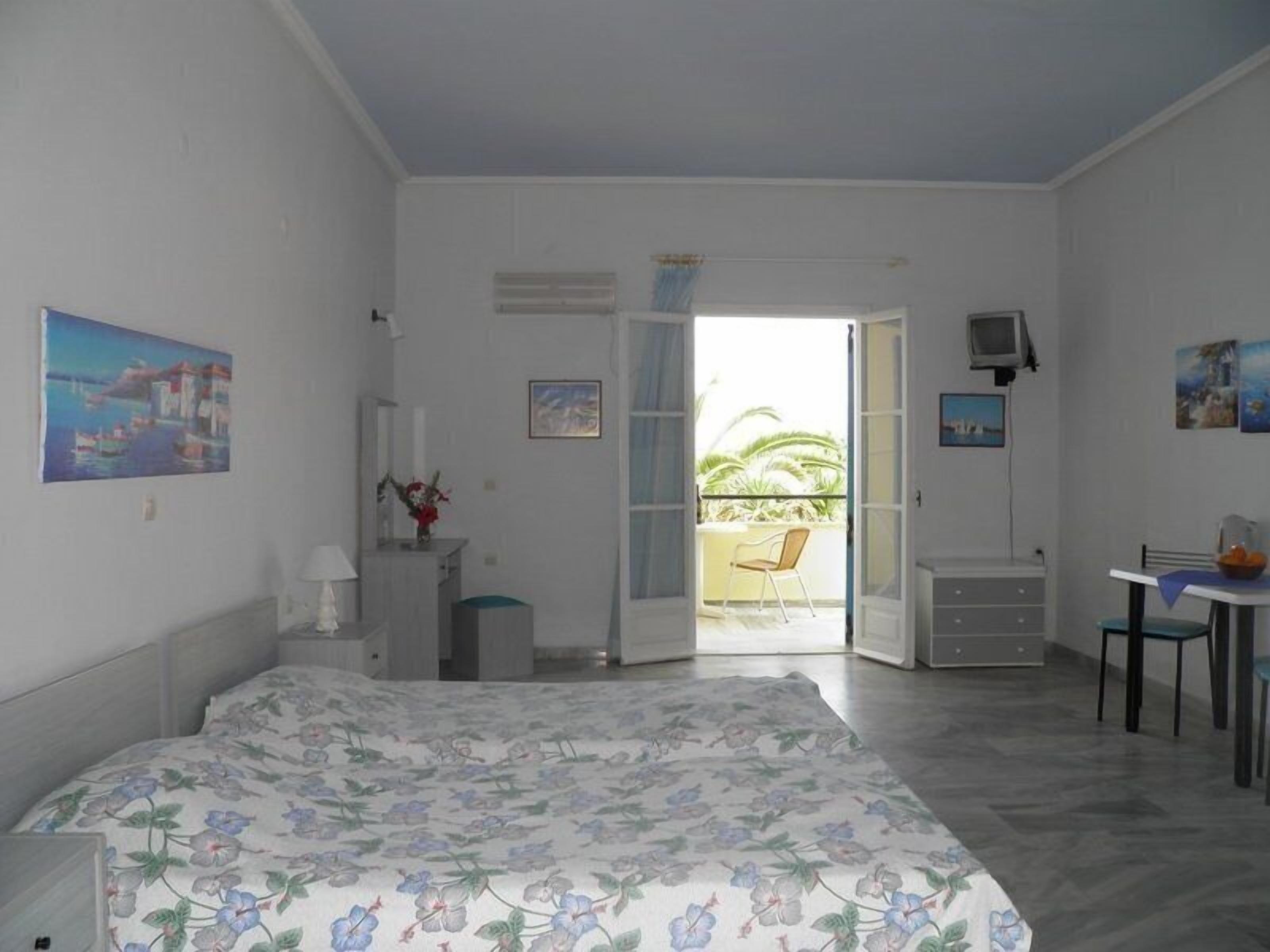 Une chambre à coucher avec un lit, un bureau, une chaise et un balcon.