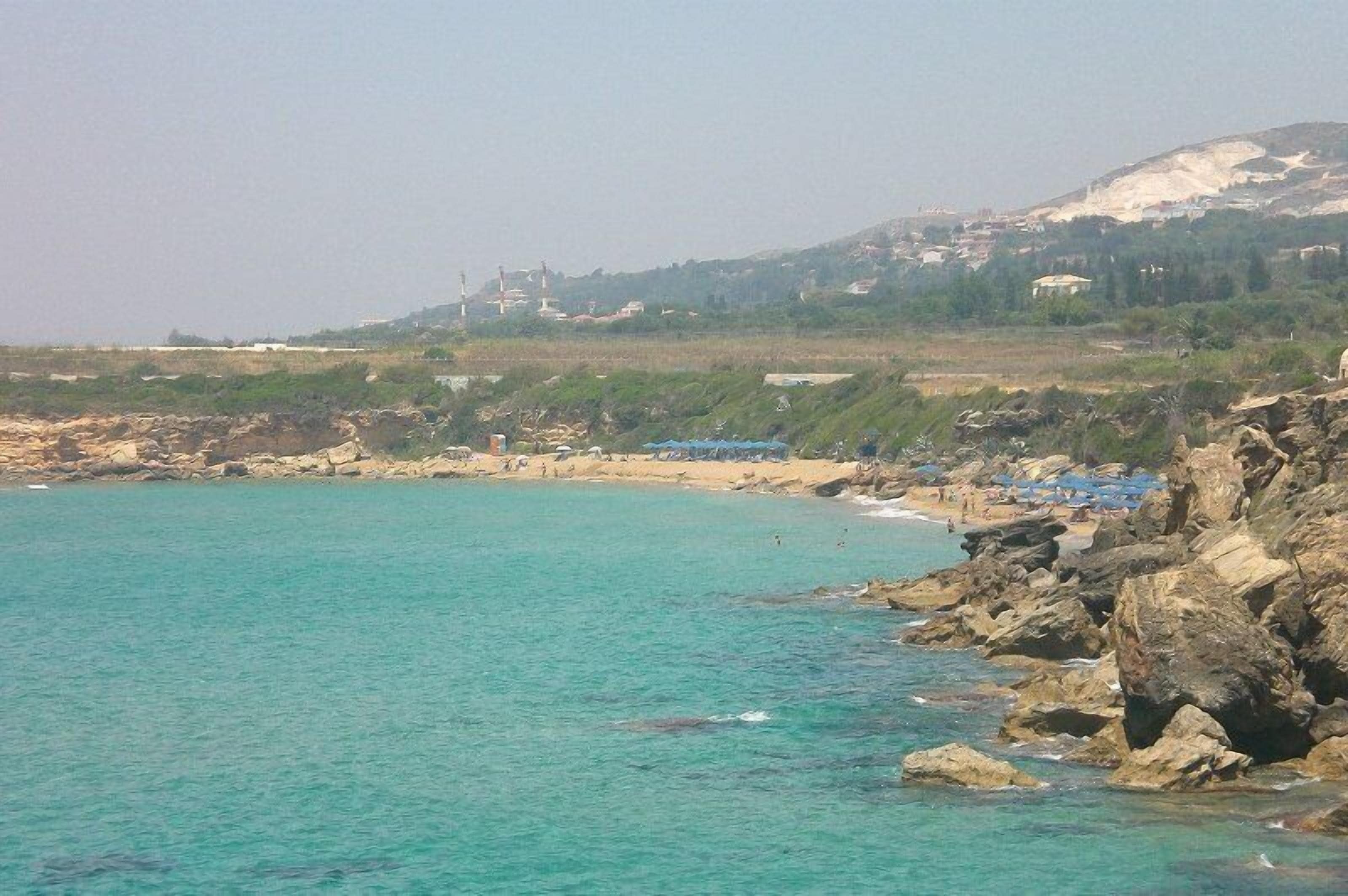 A coastal beach with rocky terrain and a clear view of the sea.