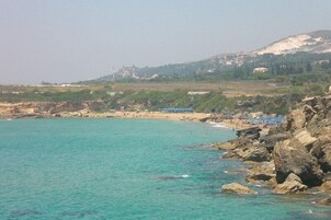 Una playa costera con terreno rocoso y una vista despejada del mar.