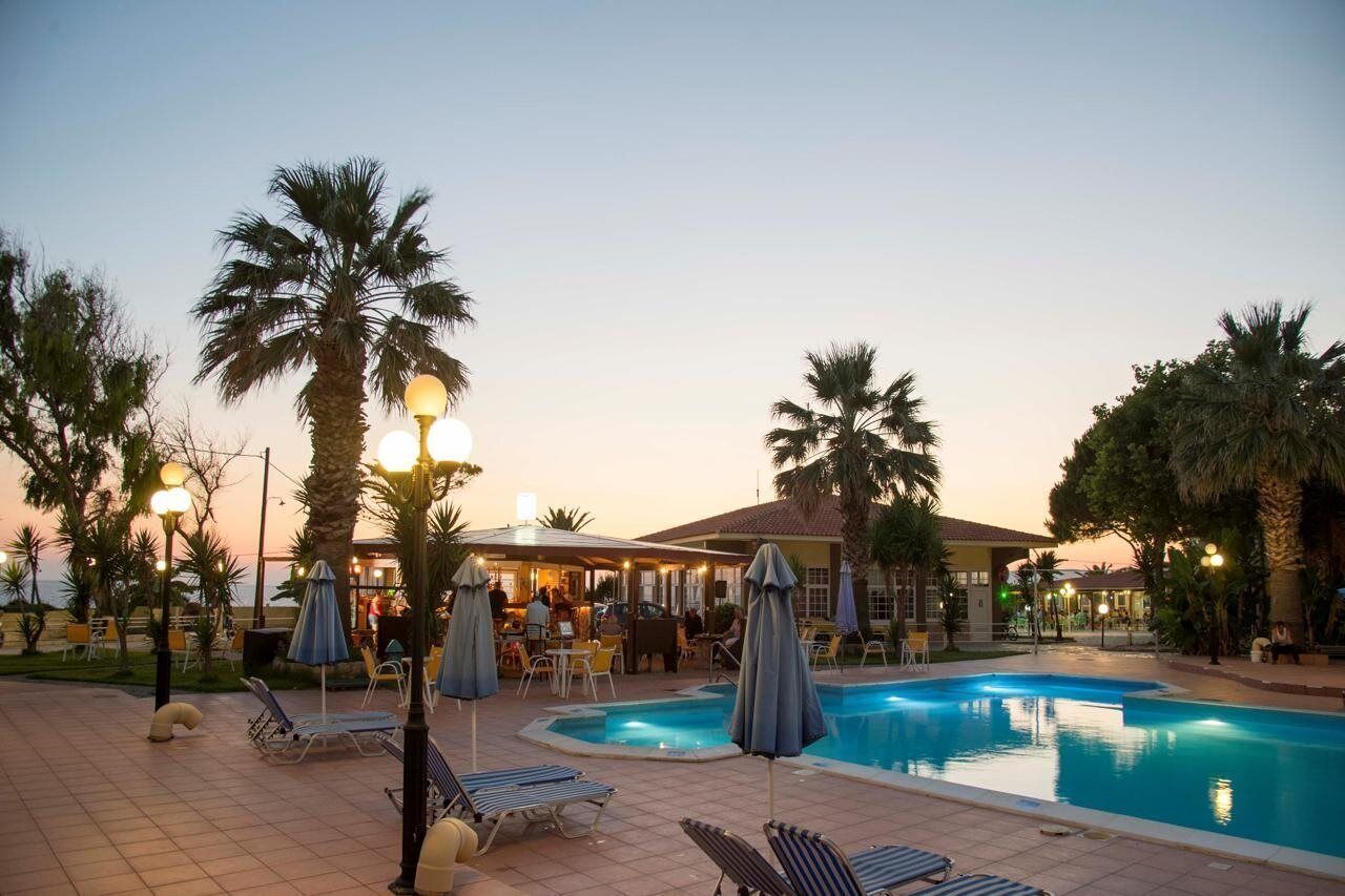 A poolside area with lounge chairs, umbrellas, and a bar area.
