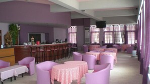 A hotel lobby with a bar area, multiple seating arrangements, and a television screen. - Ammes Hotel & Apartments (Kefalonia)