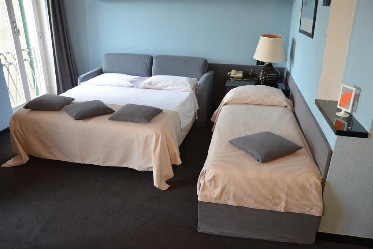 Two single beds with headboards, a bedside table with a lamp, and a small table with a phone and a picture frame.