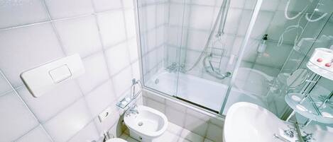 A bathroom with a glass-enclosed shower, two sinks, and a toilet.