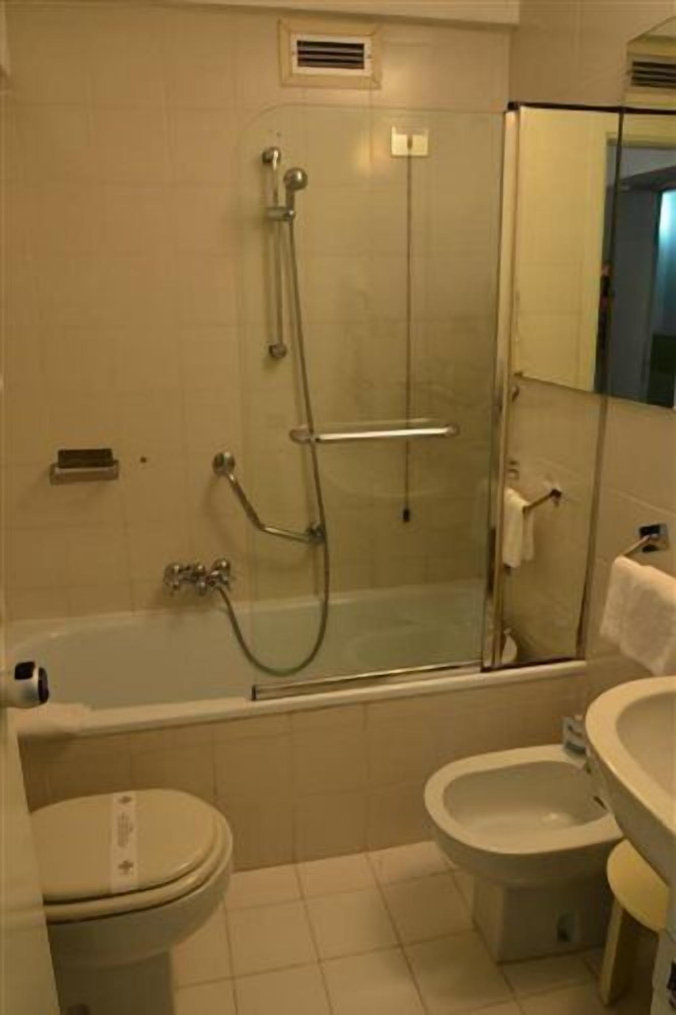 A bathroom with a glass-enclosed shower, a bathtub, a toilet, and a bidet.