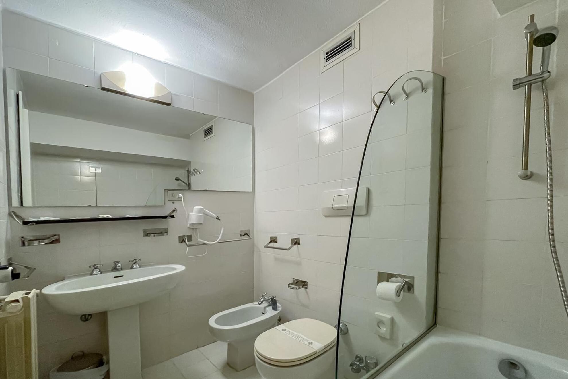 Une salle de bain comprenant des toilettes, un bidet, un lavabo et une douche.