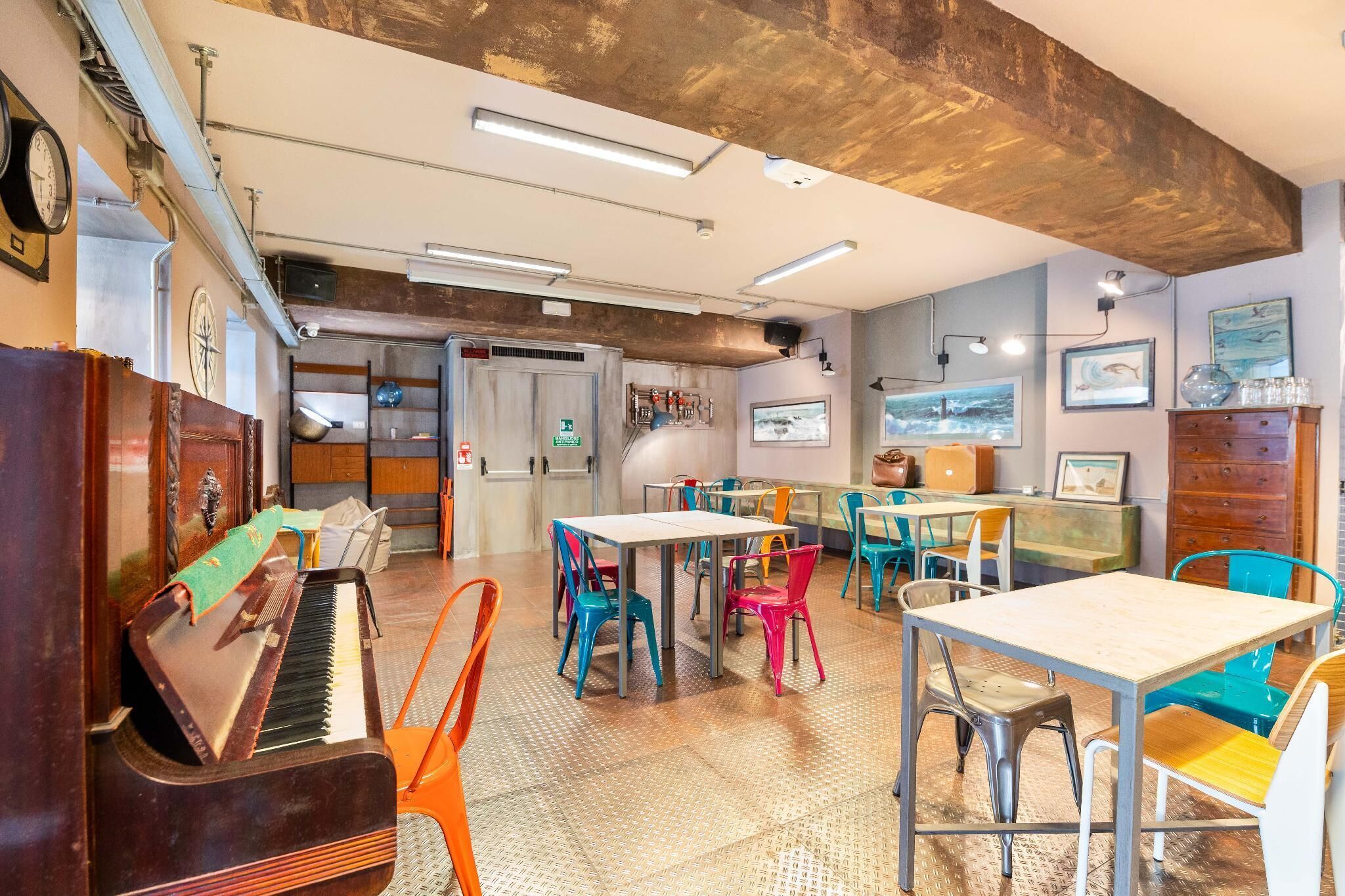 A room with a piano, colorful chairs, tables, and artwork on the walls.