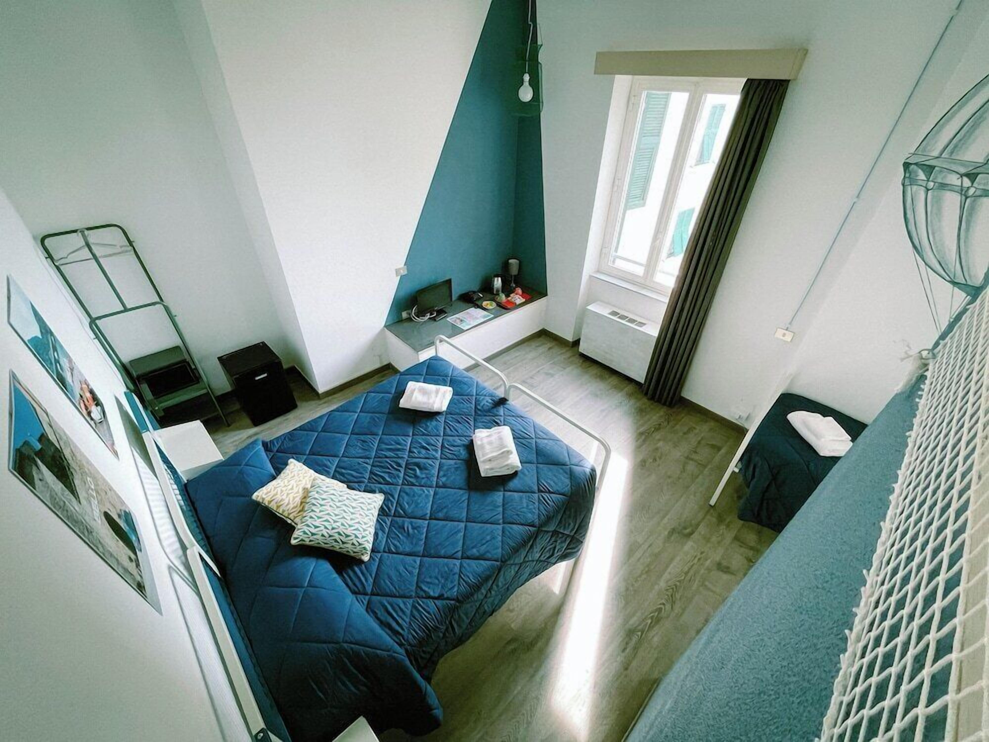Una habitación con cama, escritorio, silla, ventana y lámpara colgante.