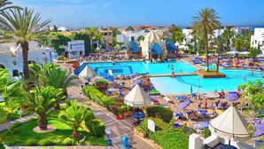 A resort with multiple swimming pools, palm trees, and beach umbrellas. - Caribbean Village Agador (Agadir)