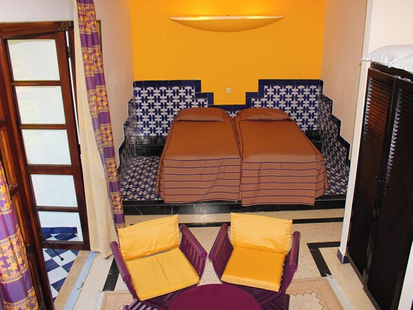 Une pièce comprenant un lit, deux chaises, une table et une armoire.