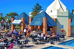 An outdoor pool area with tables and chairs, a sign reading 'Happy Valentine's Day,' and a building with a distinctive blue roof. - Caribbean Village Agador (Agadir)