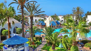 A resort with multiple swimming pools, palm trees, and a beach area.