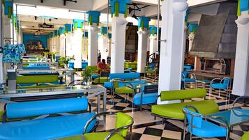 A restaurant with checkered flooring, green and blue seating, and a visible bar area.