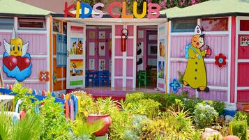 Un club infantil lleno de color con un aspecto divertido, que incluye personajes de caricaturas y una pared de flores.