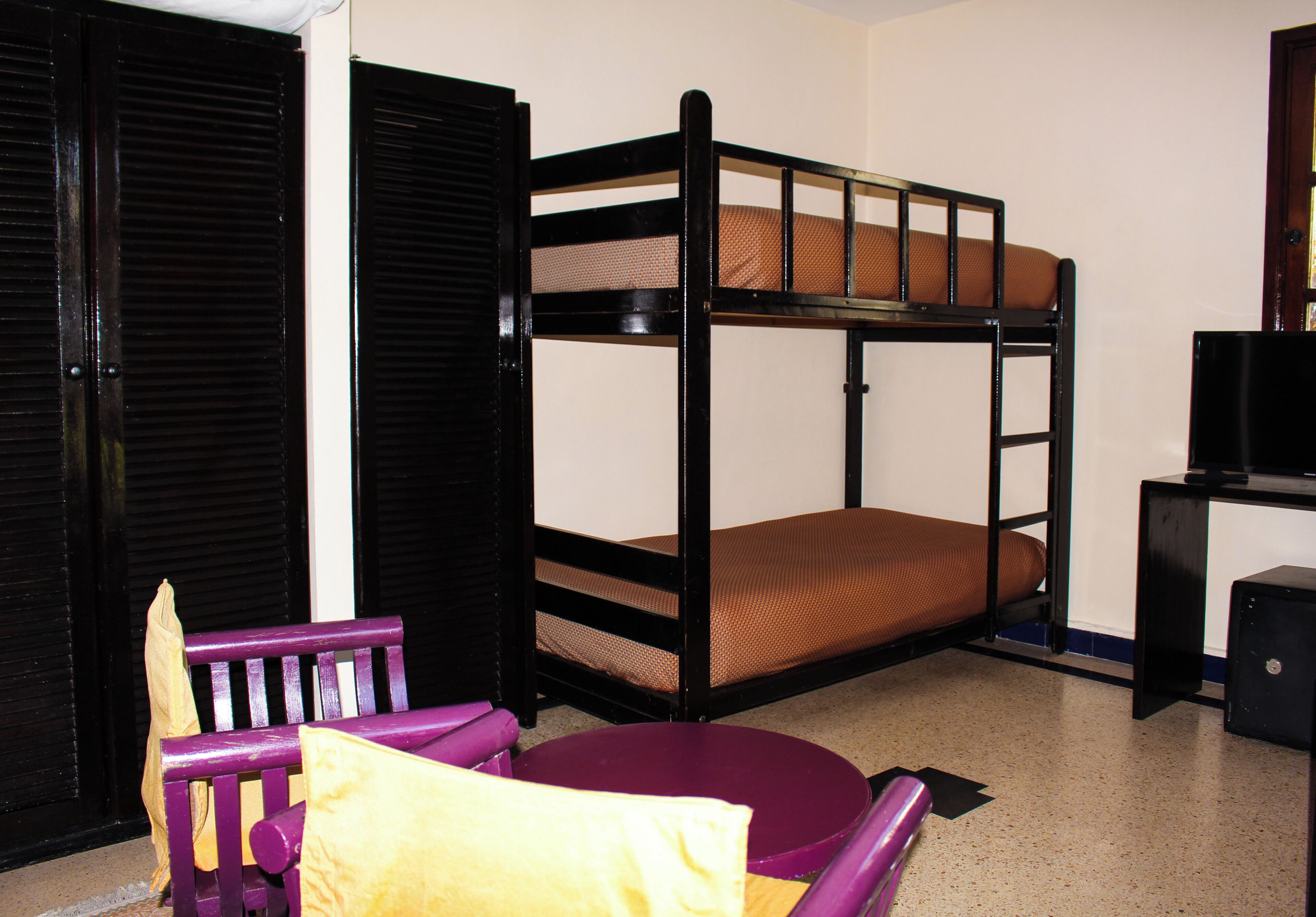 Un lit superposé avec un matelas, une chaise violette et une petite table.