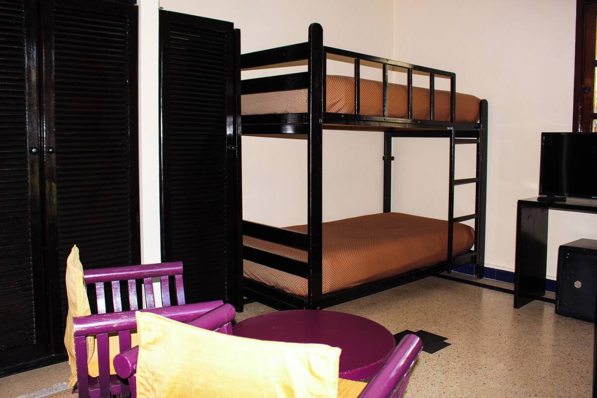 A bunk bed with a mattress, a purple chair, and a small table.