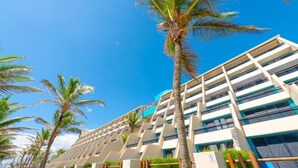A modern hotel with a multi-story structure, outdoor seating, and palm trees. - Ocean Palace All Inclusive Premium (Natal)