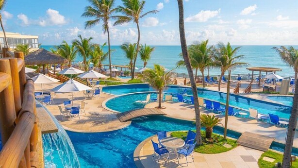 A pool area with multiple water features, lounge chairs, and palm trees. - Ocean Palace All Inclusive Premium (Natal)