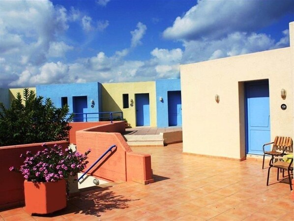 A hotel courtyard with multiple rooms, a tiled floor, and a potted plant. - Scaleta Beach Hotel (Rethymno)