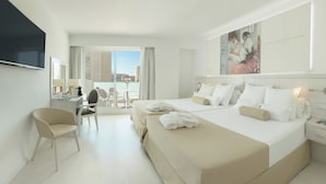 A hotel room with a large bed, a desk with a chair, a TV, and a view of the city. - Villa Luz Family Gourmet & All Exclusive Hotel (Gandia)