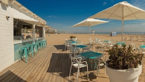 A beachside bar with outdoor seating, including tables and chairs, and large umbrellas. - Villa Luz Family Gourmet & All Exclusive Hotel (Gandia)
