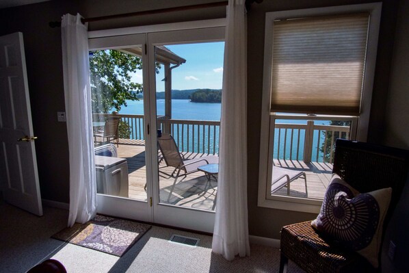 Ein Zimmer mit einer Schiebetür zu einer Terrasse mit Gartenmöbeln und Seeblick.