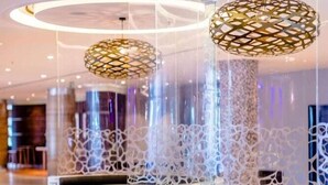 A modern seating area with circular platforms, a patterned ceiling light, and a decorative wall. - Southern Sun Rosebank (Johannesburg)