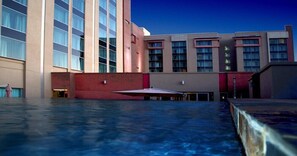 Un hotel con una amplia piscina exterior, varios pisos y un diseño arquitectónico moderno.
