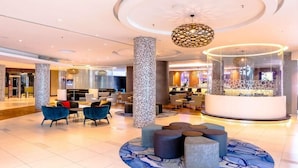 A spacious lobby with a central seating area, a reception desk, and a modern chandelier. - Southern Sun Rosebank (Johannesburg)