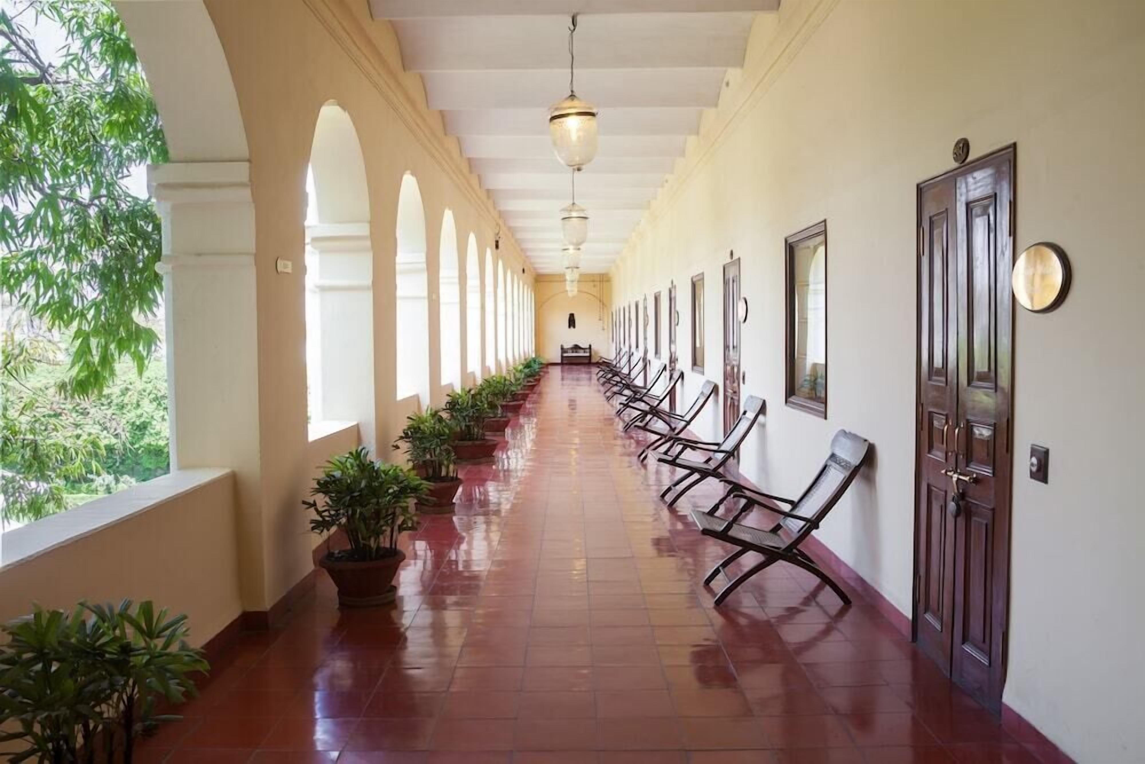 A corridor with a row of benches, a ceiling light, and a door on the right.